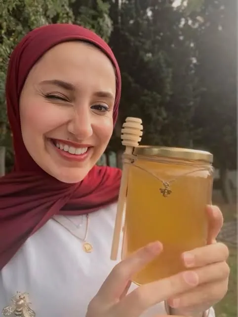 Melike, göz kırparak elindeki bal kavanozunu gösteriyor